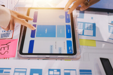 Close up ux developer and ui designer brainstorming about mobile app interface wireframe design on table with customer breif and color code at modern office.Creative digital development agency.