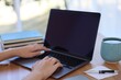 © New Africa - Woman working with laptop at table against blurred background, closeup