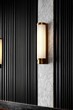 © The - Interior shot showcasing a wall lamp mounted on a marble pillar, flanked by dark ribbed panels