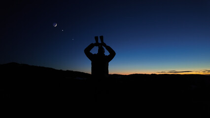 Wall Mural - Amateur astronomer looking at the evening skies, observing planets, stars, Moon and other celestial objects with binoculars.