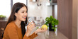 © Fahng - Asian attractive female in kitchen holding green apple and a glass of water drinking fresh water after wake up in morning for health.