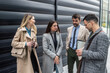 © Srdjan - IT experts freelance workers innovative technology developers, working on a new project staff meeting with casual talk in formalwear outside office building before the work. Discussing business people