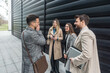 © Srdjan - IT experts freelance workers innovative technology developers, working on a new project staff meeting with casual talk in formalwear outside office building before the work. Discussing business people