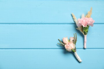 Wall Mural - Stylish boutonnieres with flowers on light blue wooden table, flat lay. Space for text