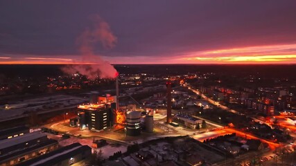 Wall Mural - Evening aerial of energy facility at sunset with glowing smoke stack and lights