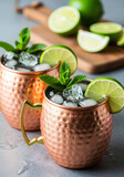 Two refreshing moscow mule cocktails in copper mugs with ice, lime, and mint garnish