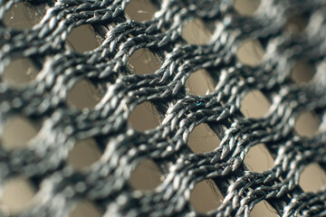 Macro closeup of black synthetic woven fabric mesh with braided threads and geometric grid pattern