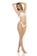 © vladimirfloyd - Studio shot of full body woman in white bikini standing barefoot with arms raised and one leg on tiptoes on white background.
