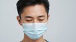© The 2R Artificiality - Young man wearing medical face mask looking down against neutral white gray background focused on health and hygiene practices