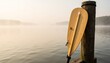 © Наталья Титова - Wooden paddle resting on a post by a misty lake at dawn