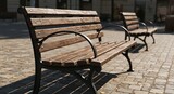 Perspective view of empty park benches on a cobblestone plaza under the bright sun. The long shadows and repeating forms create a tranquil scene, symbolizing a quiet moment, rest, or waiting.