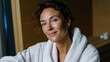 © Milos - A serene portrait of a woman in a soft white robe, highlighting her peaceful expression, showcasing relaxation and comfort, set in a calming environment.