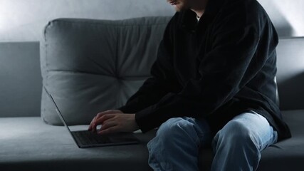 A freelancer in a black shirt works on a gray sofa at home on a laptop.
A computer specialist works on a laptop.
Typing on a laptop keyboard.
Work, freelancing, technology