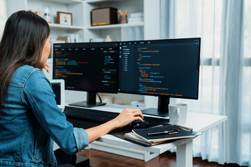 Young Asian in IT developer creating with typing online information on pc with coding program data of website application, wearing jeans shirt. surrounded by safety analysis two screens. Stratagem.