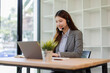 © David - Happy young asian woman Call Center Person wearing a headset, providing support at a call center, smiling while typing on computer keyboard