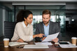 © Bogdan.Vision - A man and woman sitting at a table looking at paperwork