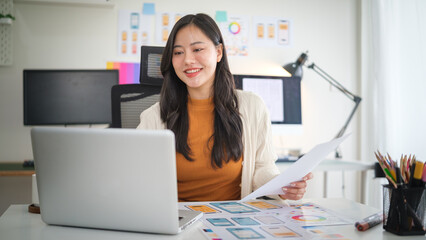 UX UI designer working on website interface project, analyzing wireframes and prototypes on laptop in creative office.