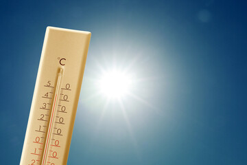 Wall Mural - thermometer showing high temperature against sky with bright sun. extremely hot weather