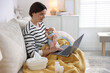 © New Africa - Telehealth. Smiling mother with her baby having online consultation with doctor by laptop on sofa at home