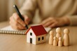 © ParinApril - Family and Home Concept with Wooden Figures and Notepad on a Table for Real Estate Representation