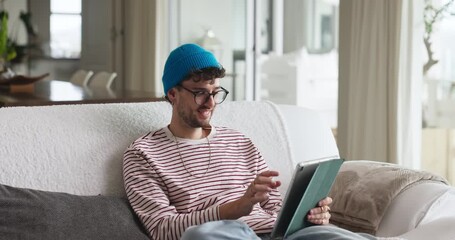 Happy, tablet and man in home with research for education, learning or college application. Ideas, planning and male person on sofa with digital technology for online student loan in apartment.
