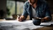 © Bussakon - A man focused on planning and writing on documents with a coffee mug on his desk