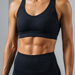 © Vellari - Fit young woman with toned abs posing in sportswear against gray background