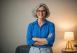 © Photos stock  2.0 - Confident senior woman wearing blue shirt with arms crossed smiling wearing glasses indoors illuminated by warm lamp light
