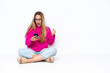 © luismolinero - Young caucasian woman sitting on the floor isolated on white background surprised and sending a message