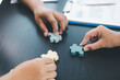 © doidam10 - Business teamwork concept with people holding wooden puzzle pieces together, symbol of collaboration, strategy, problem solving, partnership and corporate success in modern office. business teamwork.