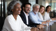 © Kateryna - A diverse leadership team of five executives sits around polished conference table during strategy meeting CEO at head gesturing toward presentation screen while others take notes