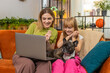 © Andrii Iemelianenko - Mother and daughter with French bulldog at home finish laptop game get positive victory test result cheer clap. Woman and girl with dog on sofa celebrate win share celebrate good news smile hug reward