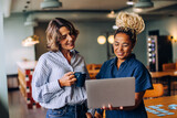Two women discussing work while looking at a laptop in a casual setting