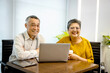© Stella - Portrait of two happy smiling senior businesspeople work together with laptop computer during drink coffee. Elderly Asian businesswoman and mature manager look at camera and smile in office workplace.