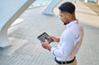 © Lumos sp - Portrait of a young  businessman wman using a tablet computer  in a city park, surrounded by modern corporate office buildings architecture
