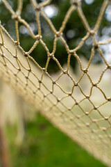 Close-up of a handmade fishing net with a soft green background