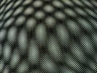 Abstract close-up of black mesh fabric with circular light pattern and geometric texture. Modern industrial textile background ideal for design, material, or technology concepts