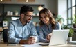 © wu - Business professionals discussing work at office desk. Woman pointing at laptop while man holding coffee observes. Teamwork and communication in corporate environment with focus on technology.