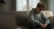 © Vyatcheslav - Depressed teenage boy sitting alone on a sofa in a living room. Stressed and worried adolescent feeling lonely. Youth mental health and anxiety concept