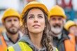 © EUT - Young female worker looks up surrounded by male construction team. It shows ambition, teamwork, and forward thinking in business.