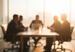 © Andrew - Blurred silhouettes of a business team meeting in a modern office with bright backlighting.
