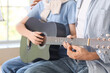 © Pixel-Shot - Boy taking guitar lessons from private music teacher in room, closeup