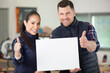 © auremar - male and female colleagues holding blank sign with thumbs up
