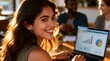 © Lazuardi - Portrait of a successful and confident young businesswoman smiling at the camera while working on data analysis charts on her laptop in a modern, sunlit office