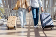 © Anastasiya - Closeup of mature travelers holding hands while pulling suitcases at airport