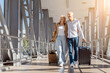 © Anastasiya - Happy senior family couple smiling while walking in airport with suitcases