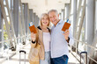 © Anastasiya - Happy senior travelers holding passports and tickets at airport