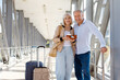 © Anastasiya - Smiling mature couple standing at airport with luggage and passports