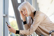 © Anastasiya - Worried mature woman checking smartphone at airport corridor, suffering problems