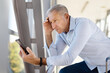 © Anastasiya - Worried mature man checking smartphone at airport corridor, suffering problems